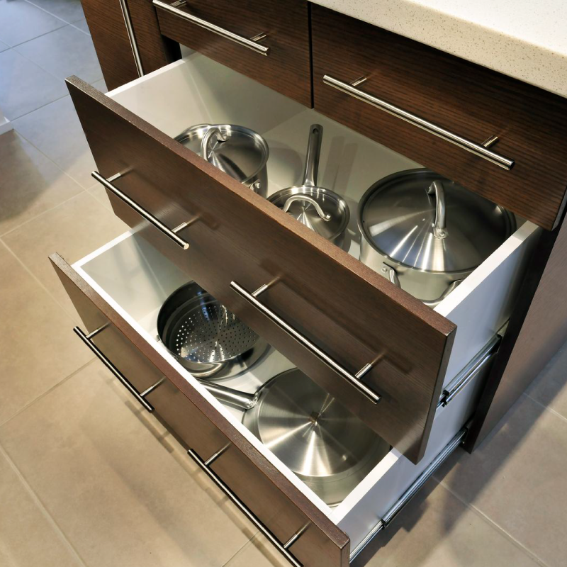 Open cabinet drawers with pots and pans